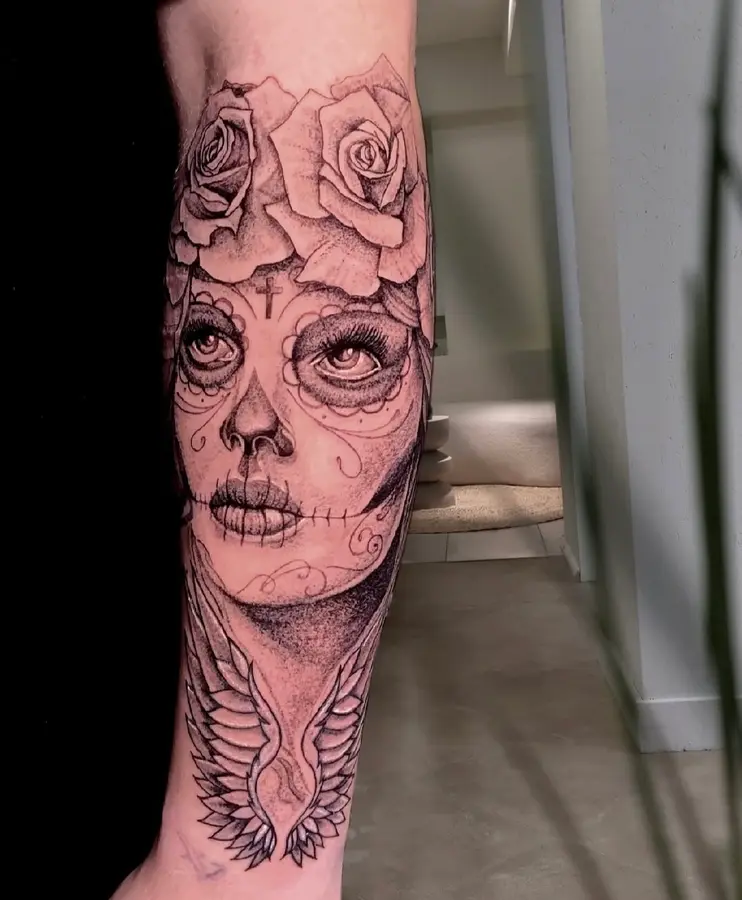 Black-and-Grey-Realismus am Unterarm: Catrina-Gesicht mit Rosen und Flügeln
